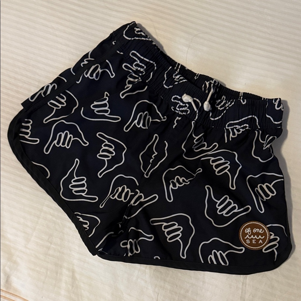 Of One Sea Black Swim Shorts with White Hand “Shaka” print